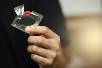 Ready-to-use condoms in male hand ,
concept on the bed Prevent infection.