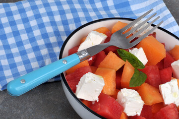 Salade composée avec du melon, de la pastèque et de la feta servie dans une assiette avec une...
