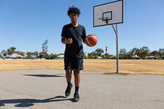 tall teenage basketball player on outdoor court with basketball