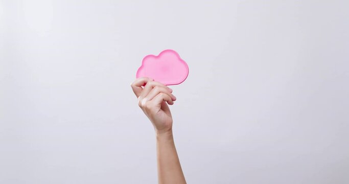 Woman's hand shows a cloud icon color pink symbol in white studio background with copy space.