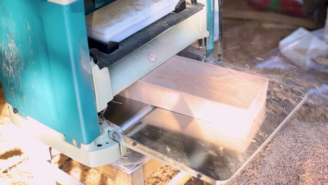 Woodworking planer electric machine with boards in it.
