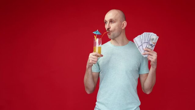 All-inclusive trip. Rich man. Enjoying vacation. Confident guy drinking fresh summer cocktail with straw holding cash dollars on red background copy space.