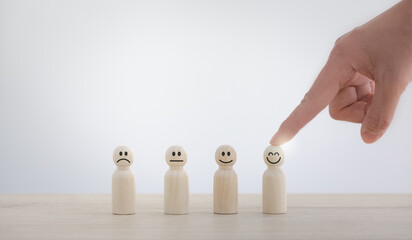 closeup businesswoman hand picking happy emotion face on wooden piece arranged on table for...