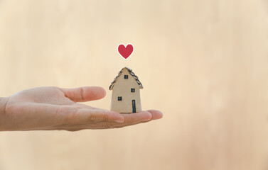 hand holding home model with heart