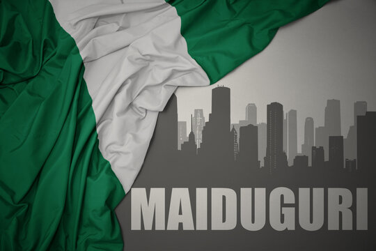abstract silhouette of the city with text Maiduguri near waving colorful national flag of nigeria on a gray background.
