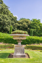 Edwardian stone tazza planter with growing flowers in a public park, UK.