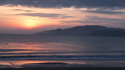 seacoast landscape before sunrise with  silhouettes of mountains in the distance ,cloudy sky, peaceful sea. No people. Travelling , vacations ,rest near the sea concept.