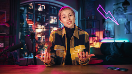 Confident Young Female Talking Into Microphone While Recording Radio Show from Her Loft Apartment. Happy Woman with Short Hair Talking on Camera and Recording Podcast Live on Social Media.