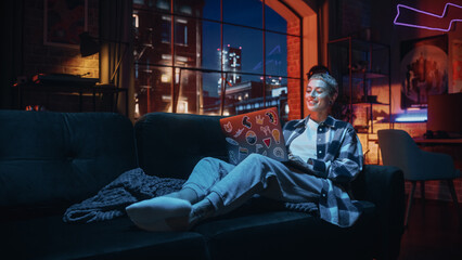 Young Beautiful Woman Working from Home on Laptop Computer with Stickers in Cozy Stylish Loft Apartment. Creative Female Smiling, Checking Social Media, Browsing Internet. Flat with Big Windows.