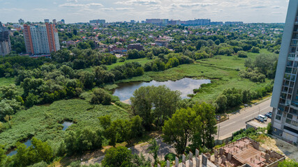 Fototapeta na wymiar Drone aerial view marshy lake in the metropolis, summer nature in sunny day, green trees