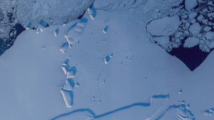 Top view satellite image of icebergs casting long shadow along the Antarctic coast in Antarctica. Elements of this image furnished by NASA.