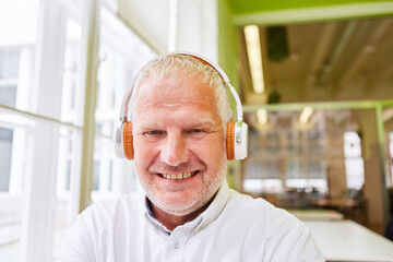 Elderly man with headphones smiles while listening to music