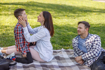 Happy beautiful mother hugging and being proud of small son. Man with family on picnic.