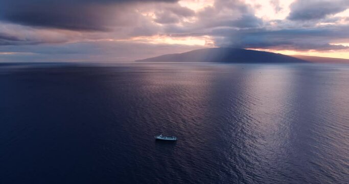 flying backwards looking at yacht sailing with lanai island in the back while sun sets