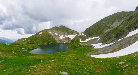 panoramic view of a lake in fagaras mountains. summer landscape on a cloudy day. travel season in romania