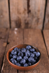 Fresh blueberries in a small bowl on a wooden table