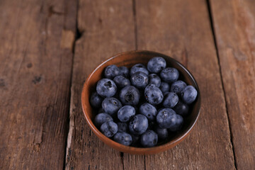 Fresh blueberries in a small bowl on a wooden table