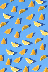 Fototapeta premium Irregular pattern of sliced oranges fruit on a blue background. Summer aesthetic citrus fruit concept.