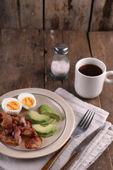 Breakfast with bacon, eggs and coffee on a wooden table