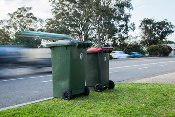 Two council bins awaiting collection beside a busy road
