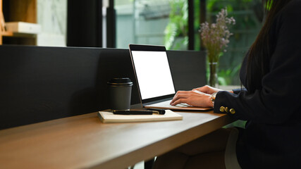 Side view young woman office worker using laptop at wooden counter bar in contemporary office