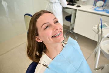 The smile of a young and beautiful girl with braces on her white teeth. Straightening of crooked...