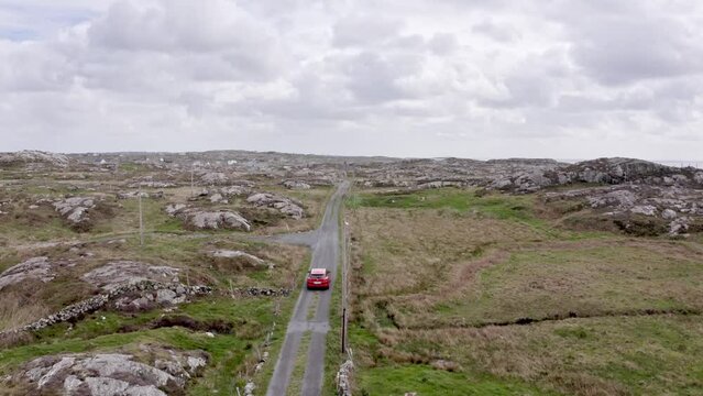 Aerial view summer road: red car travel view,drive. Gorgeous irish fields,nature scene with roadway against trough rocks and characteristic village.Atlantic ocean in background