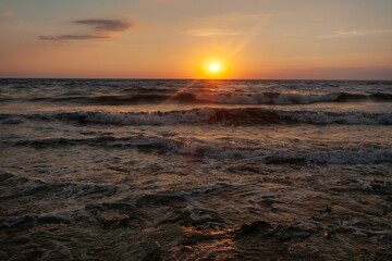 Obraz premium Evening orange sky with dramatic clouds and sea