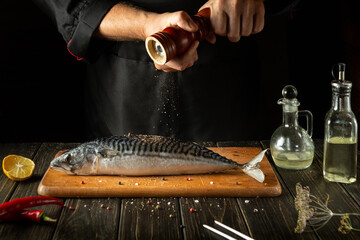 Fish chef prepares fresh mackerel in the kitchen. Scomber must be added with aromatic pepper before...