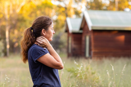 woman in profile outside weatherboard cottage in the country