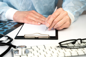 Male doctor writes out a prescription for a patient in the clinic. Medicine and healthcare. Close-up. Selective focus.