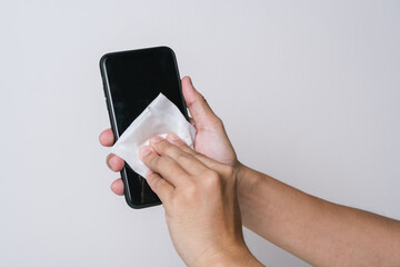 Close up of the hand wiping the mobile phone with the alcohol sanitiser wipes  to clean and prevent the spread of bacteria and virus.  Personal hygiene concept. Isolated white background
