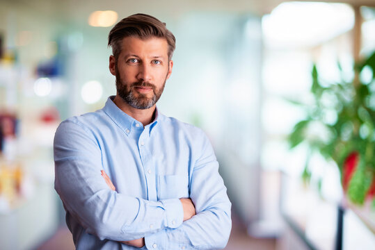 Close-up of a handsome man looking at camera and smiling while standing inside