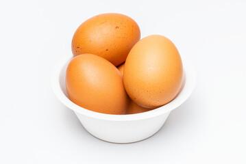 Cutout pile of brown organic egg in a biodegradable paper bowl on white background.