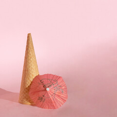 Ice cream cone standing with red umbrella. Peachy, pink, summer colors design. Hot aesthetic food concept idea. Sunny day copy space