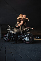 Fototapeta na wymiar Young couple kissing sitting on a motorcycle in underground parking garage