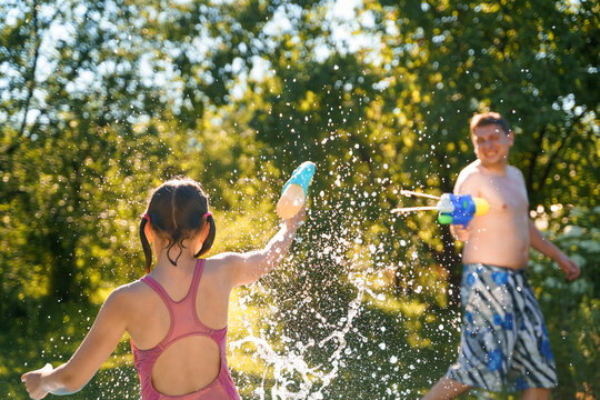 Little girl in swimwear, daughter dad, daddy, father swim, play water pistols, guns in children's inflatable pool in backyard of country house. Summer funny family outdoor games,recreation.Staycation