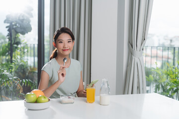 Portrait of beautiful young woman having breakfast in the kitchen.