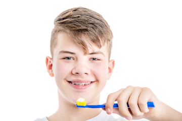 Orthodontic treatment. Dental Care Concept. Happy young smiling boy with brackets holds toothbrush