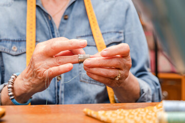 older woman's hands putting on a thimble