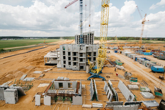 A construction site with equipment and houses, foundations, construction cranes