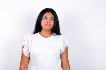 Fototapeta premium young brunette woman wearing white T-shirt standing against white wall crying desperate and depressed with tears on his eyes suffering pain and depression. Sad facial expression and emotion concept.