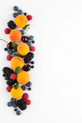 Apricots, blackberries, raspberries, blueberries, mint, cherries on a white background.Fruity background with space for writing text.