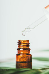 Drop of essential oil drips from pipette into bottle