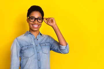 Photo of cheerful person hand touch spectacles eyeglasses look camera isolated on yellow color background