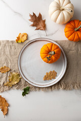 Obraz na płótnie Canvas White plate autumn leaves and pumpkin holiday table setting concept