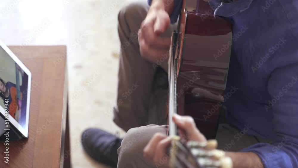 Wall mural male playing guitar with online course on tablet with mature female teacher