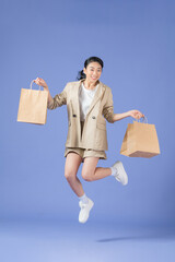 Happy young woman with shopping bags on purple background