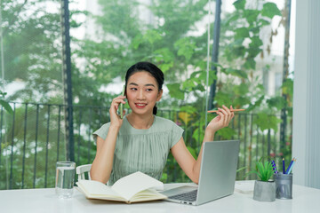 Happy Asian businesswoman talking on mobile at the office.