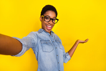 Photo of excited satisfied person make selfie arm palm hold show empty space isolated on yellow color background